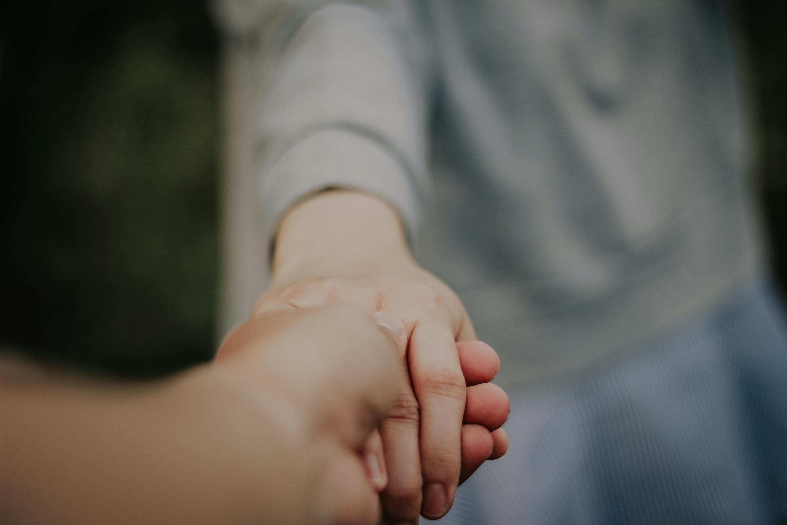 Hands holding in a gesture of connection and support, emphasizing unity and trust.